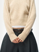 Close up of a beige sweater worn by a person with a plain background #color_warm-grey
