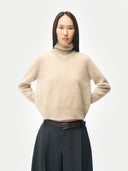 Woman wearing a beige v-neck sweater with collar and dark pants on a white background #color_warm-grey