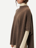 close up side view of a woman wearing a brown ribbed poncho over a white turtle neck sweater #color_cocoa