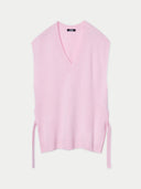 A pink V-neck cashmere maternity top with decorative ties on the side slits, displayed against a white background. #color_almond-blossom