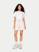 Woman wearing a white t-shirt and beige shorts on a white background #color_whisper-white