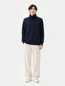 Person wearing a navy sweater and white pants on a white background #color_navy