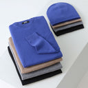 Folded cashmere sweaters in grey, olive and oatmeal on a mossy rock in autumn woodland
