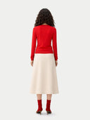 Back view of a woman wearing a red sweater and beige skirt on a white background #color_red