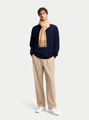 Man wearing a navy sweater, beige scarf, and pants on a white background #color_toasted-almond