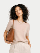 Woman holding a brown leather handbag against a white background #color_beige