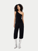 front view of Woman wearing a black one-shoulder jumpsuit with silver boots on a white background #color_black