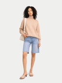 Woman wearing a beige sweater and light blue denim shorts on a white background #color_beige