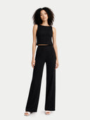 front view of Woman wearing a black sleeveless top and wide-leg pants on a white background #color_black