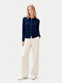 Woman wearing a navy cardigan and white pants on a light gray background #color_mood-indigo