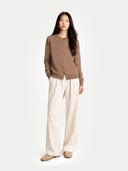 a woman standing pose with a brown crew neck cardigan and white pants #color_taupe