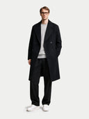 Man wearing a black coat, white shirt, and white sneakers on a light gray background #color_black