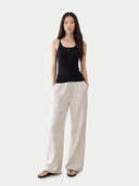 Woman wearing a black tank top and beige pants on a white background #color_black