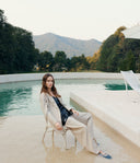 Woman sitting by a pool with mountains in the background