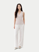 Woman wearing a light pink sleeveless top and white pants on a white background #color_lavender-blue