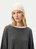 Person wearing a white knit beanie and gray sweater on a light gray background. #color_off-white