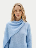 Woman wearing a light blue knitted sweater with a scarf against a white background #color_light blue