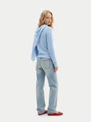 Woman standing back wearing a light blue sweater with a scarf and jeans on a white background #color_light blue