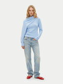 Woman wearing a light blue sweater with a scarf neckline and jeans on a white background #color_light blue