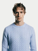 Man wearing a light blue cable knit sweater against a plain background #color_light-blue