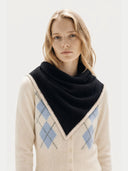 close up front view of a Woman wearing a black scarf and beige sweater with argyle pattern on a white background #color_black