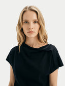 close up of a woman wearing a black short sleeve, boat neckline top against a white background #color_black