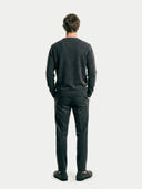 back view of a man wearing a dark gray sweater and pants on a white background.