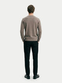 back view of a man wearing a brown long-sleeve sweater and black pants on a white background  #color_taupe