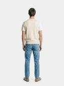 back view of a man wearing a beige vest over a white shirt and blue jeans on a white background #color-white