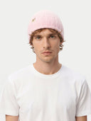 front view of a man wearing a pink beanie with a logo on a white background. #color_pink