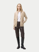 Woman wearing a beige cardigan, white shirt, brown leather pants, and black knee-high boots on a white background. #color_beige
