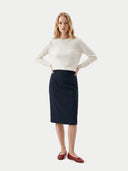 Woman wearing a white sweater and black skirt on a white background. #color_black