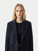 close up front view of a woman wearing a black coat on a light gray background. #color_black