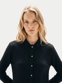 Woman wearing a black ribbed sweater against a white background. #color_black