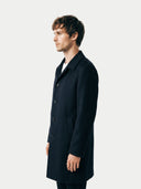 side view of a man wearing a black coat against a white background. #color_black