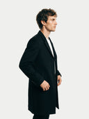 Side view of a man wearing a black coat against a white background. #color_black