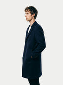 Side view of a man wearing a dark blue coat against a white background. #color_navy