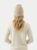 back view of a person wearing a beige knit hat and sweater on a light gray background #color_beige