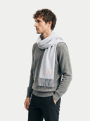 Man wearing a gray sweater and light gray scarf with a visible brand logo on a white background. #color_light-gray