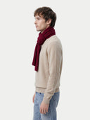 Man wearing a beige sweater and blue jeans with a red scarf on a white background. #color_bordeaux