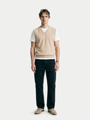 front view of a man wearing a beige v-neck vest over a white t-shirt with black pants on a white background #color_beige