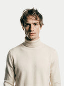 close up of a man wearing a beige turtleneck sweater against a white background #color_off-white