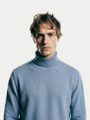 close up of a man wearing a light blue turtleneck sweater against a white background #color_light-blue