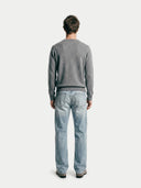 back view of a man standing wearing a gray sweater and jeans.