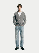 front view of a man wearing a gray v-neck cardigan, white shirt, and blue jeans on a white background #color_dim-gray