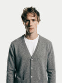 close up of a man wearing a gray v-neck cardigan with side pockets over a white shirt on a light background #color_dim-gray
