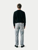 back view of a man wearing a black sweater and light blue jeans on a white background #color_black