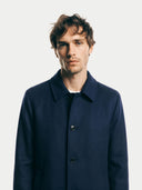 close up front view of a man wearing a navy blue coat against a plain background. #color_navy