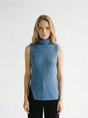 Woman wearing a blue sleeveless, turtleneck sweater against a white background #color_dusty-blue