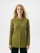 Woman wearing a green ribbed sweater on a white background #color_dark-citron